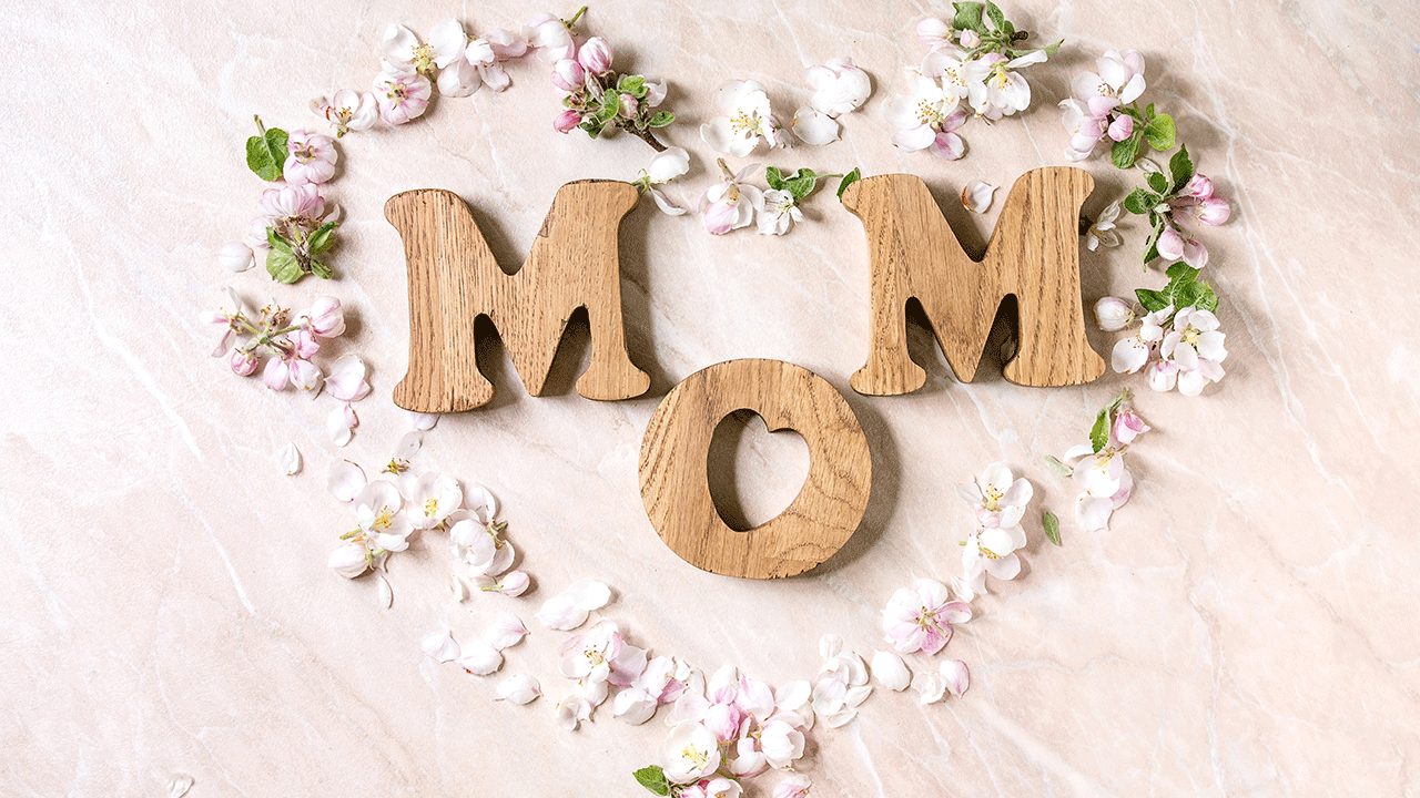 The word "Mom" spelt out with wooden letters outlined with a heart