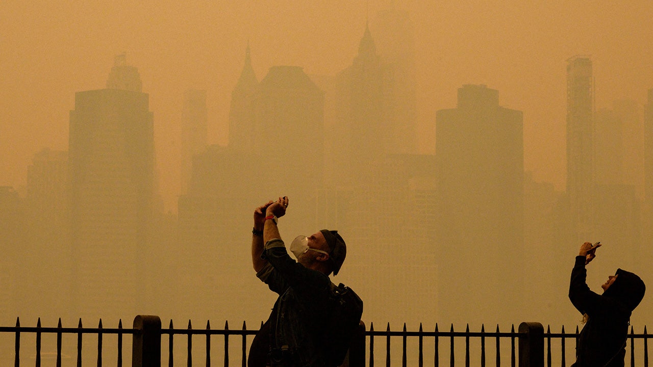 People take photos of the sun as smoke from the wildfires in Canada cause hazy conditions in New York City on June 7, 2023. Smoke from Canada's wildfires has engulfed the Northeast and Mid-Atlantic regions of the US, raising concerns over the harms of persistent poor air quality. (ANGELA WEISS/AFP via Getty Images)