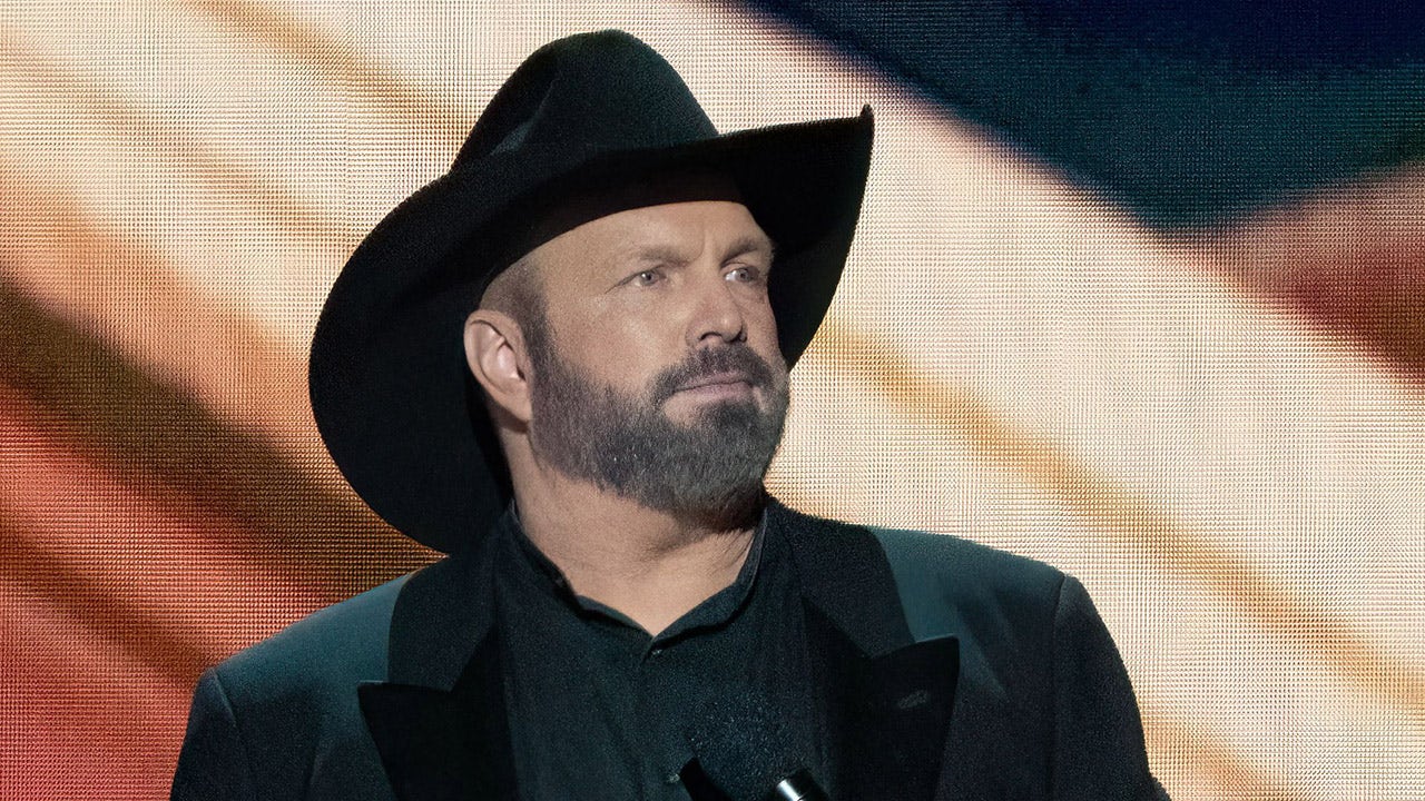 Garth Brooks performs wearing signature black hat and coat