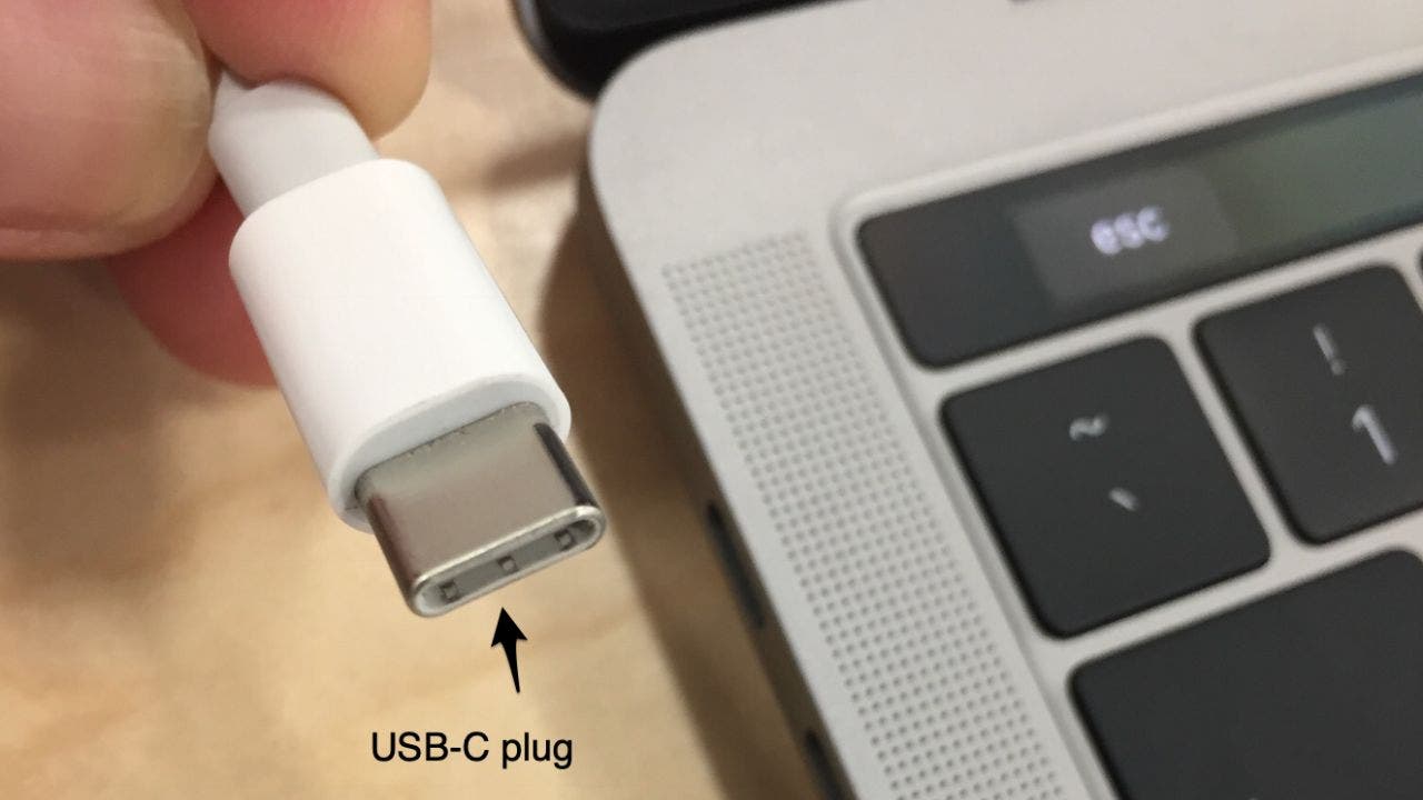 Photo of a USB-C Plug next to an Apple laptop.