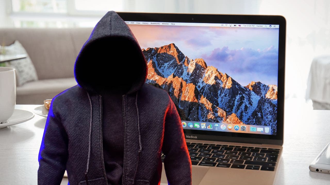 Man with no face stands in front of Mac computer