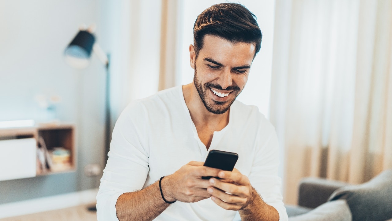 Man smiling and holding his phone.