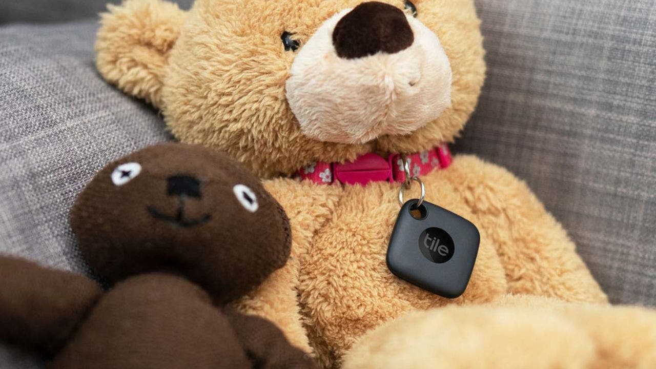 A dark brown teddy bear next to a light brown Teddy Bear wearing a Tile tag.