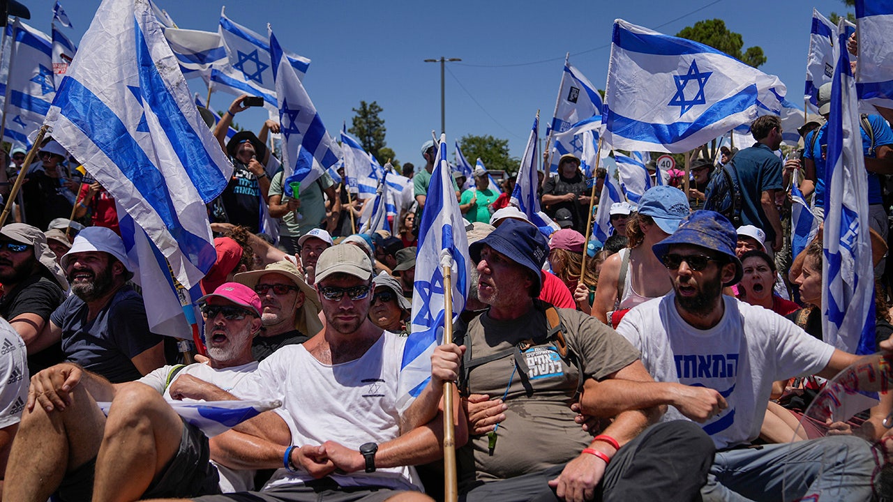 Israelische Demonstranten verschränken die Waffen und halten Fahnen