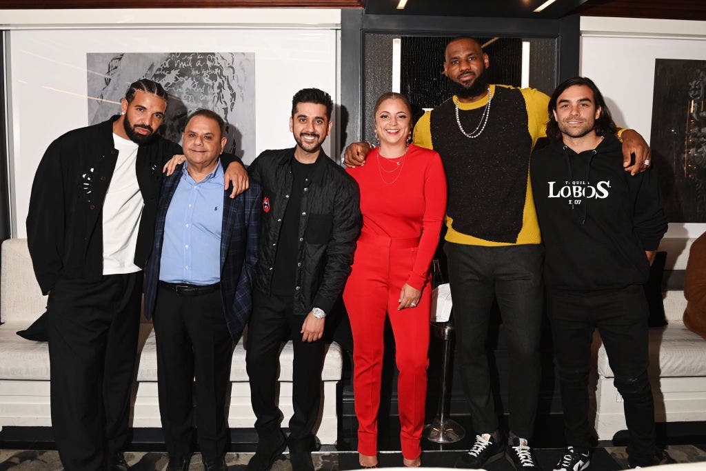 Erin Harris wears a red pantsuit and poses with Drake and LeBron James.