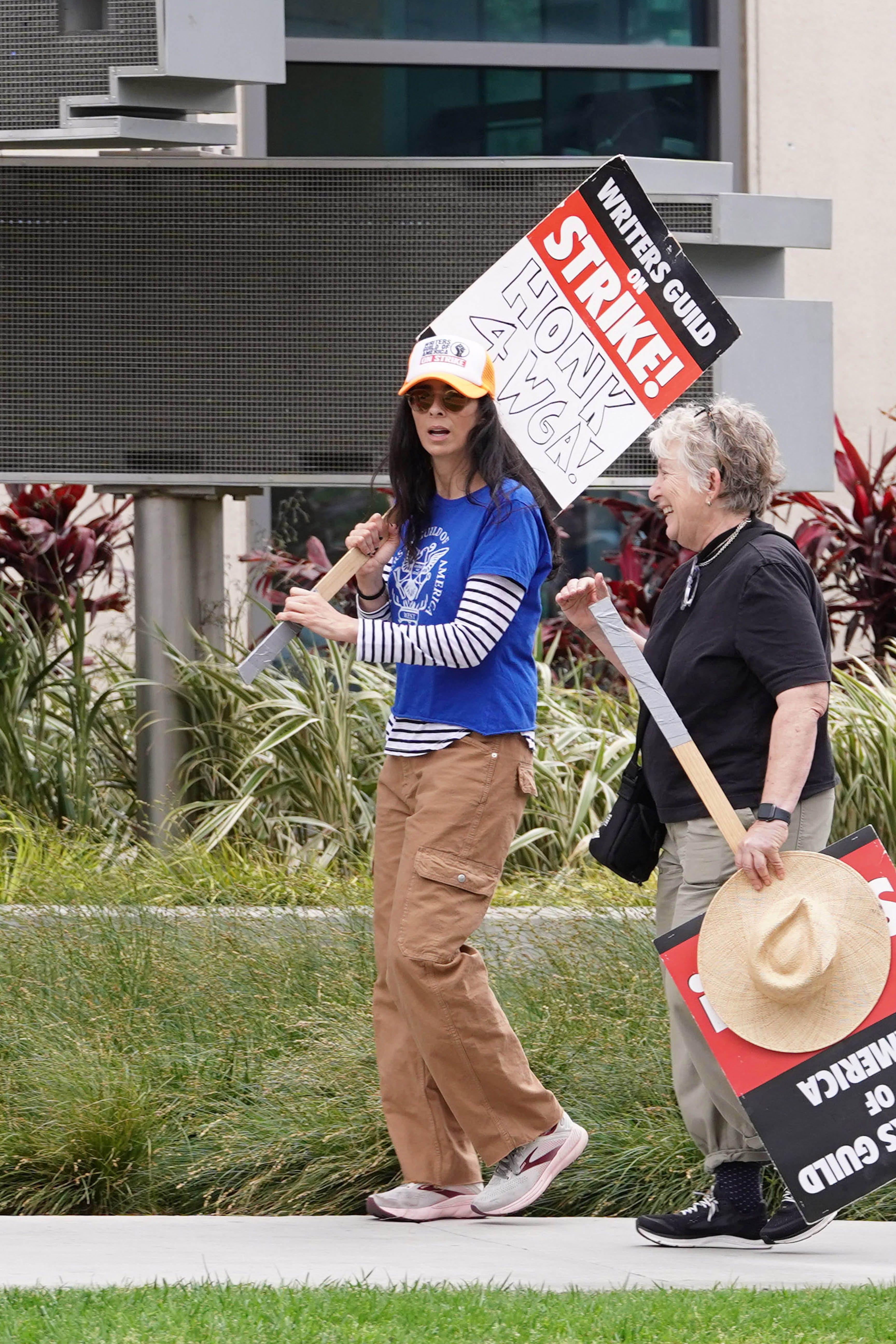 Sarah Silverman at a Writers Gild strike carrying a sign.