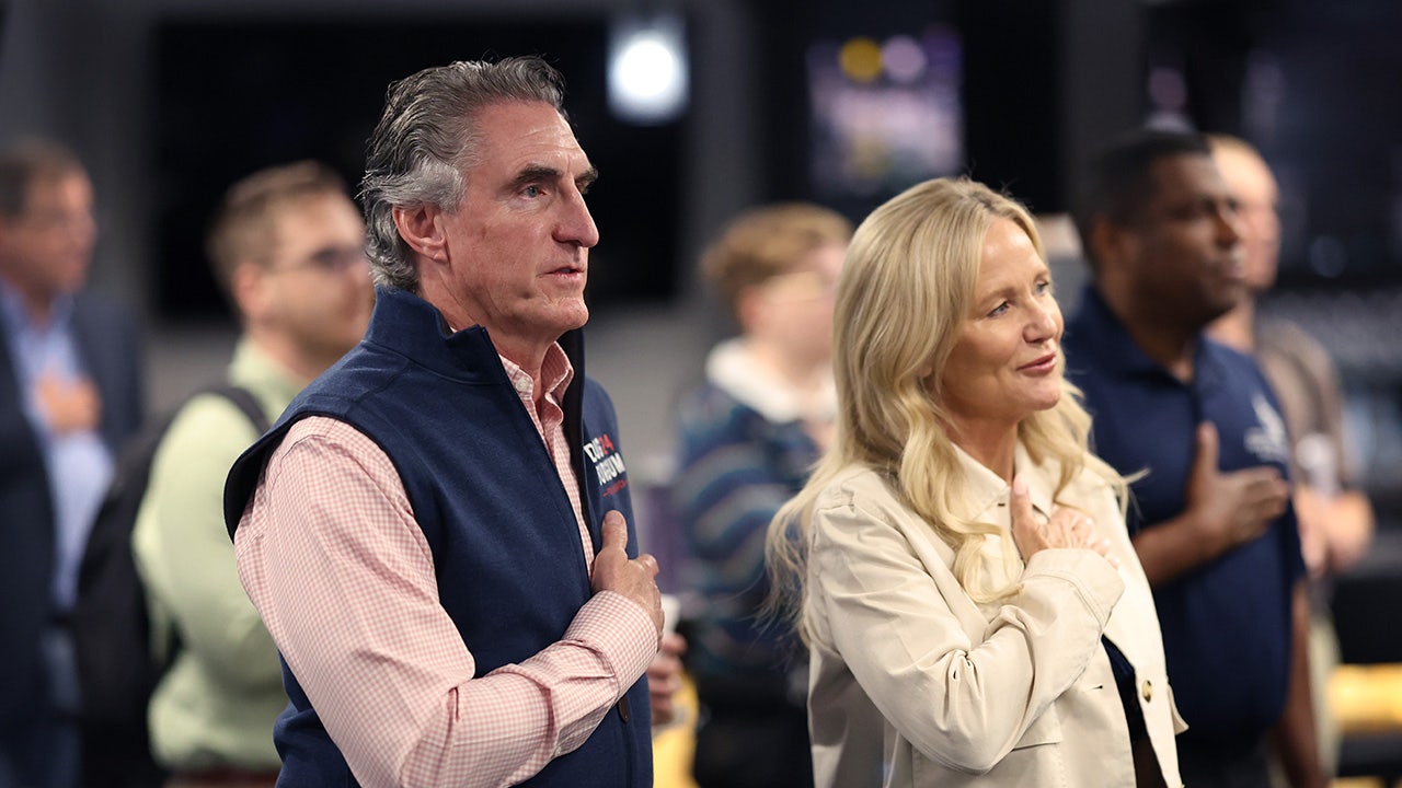 Doug Burgum and his wife place their hands on their hearts for the pledge of alliegance