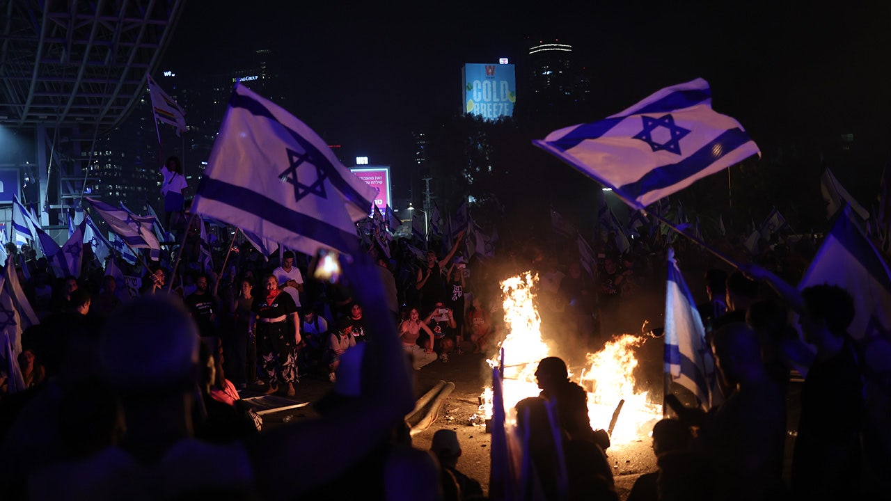 متظاهرون يلوحون بالأعلام الإسرائيلية ويشعلون النار في الشارع