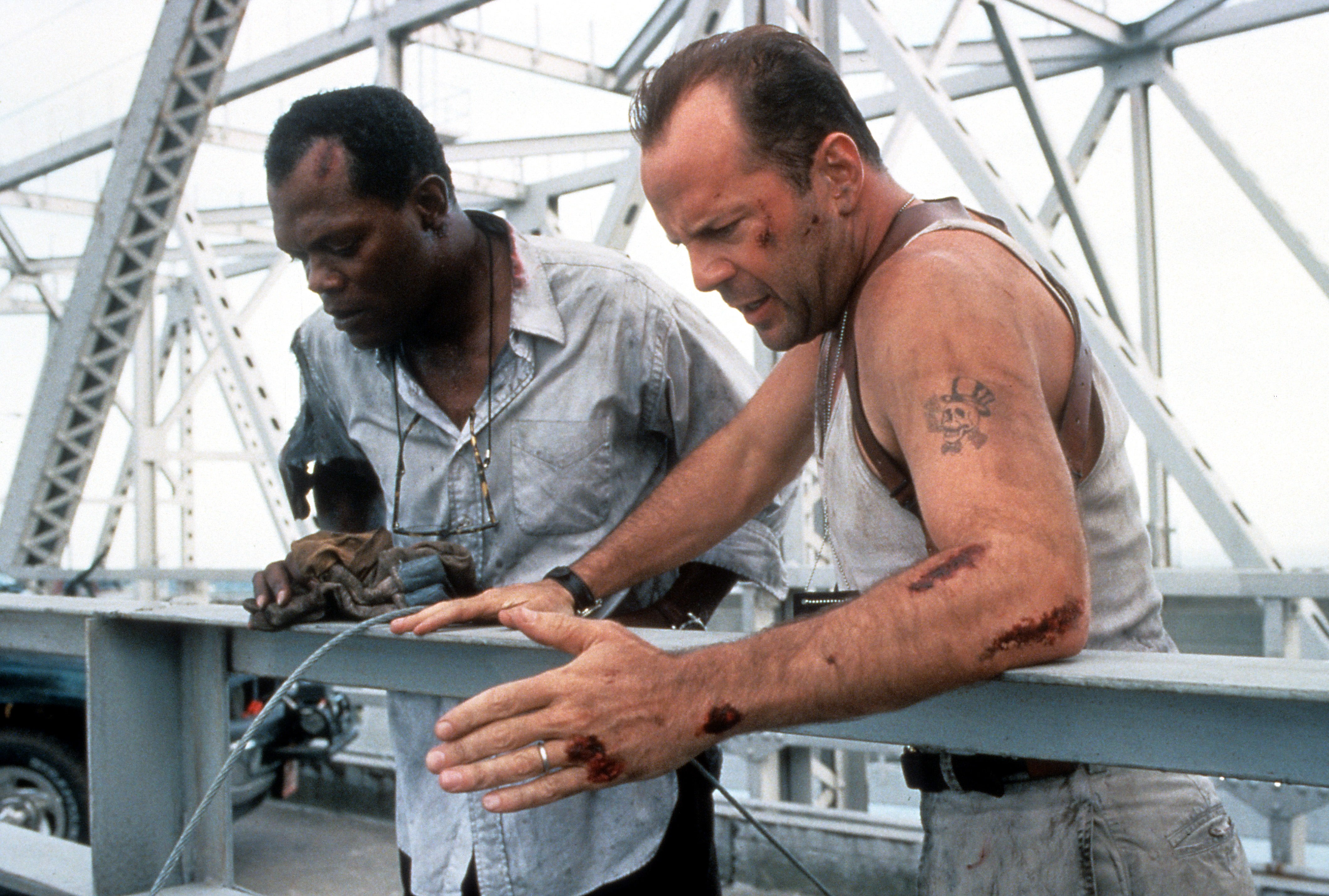 Samuel L Jackson and Bruce Willis standing on a bridge, looking down in a scene from the film Die Hard: With a Vengeance