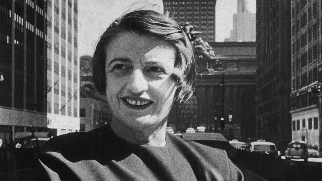 Russian-born American author and philosopher Ayn Rand smiles and stands outdoors in 1957 with her arms folded, in front of the Grand Central building, midtown Manhattan, New York City. (Photo by New York Times Co./Getty Images)