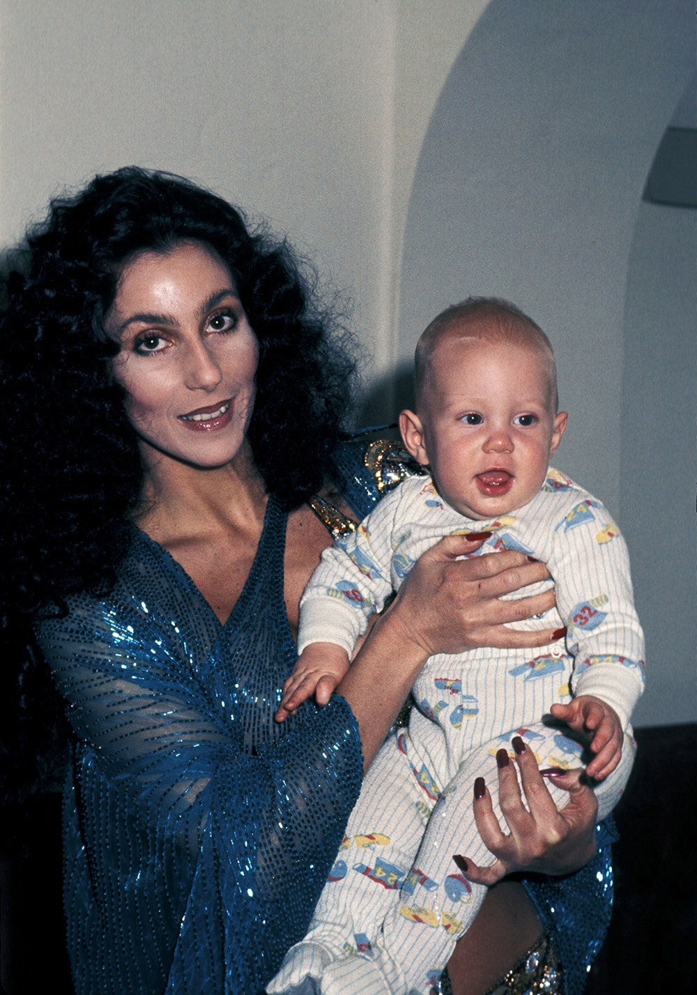 Cher wearing a blue sparkling dress holding her son Elijah Blue