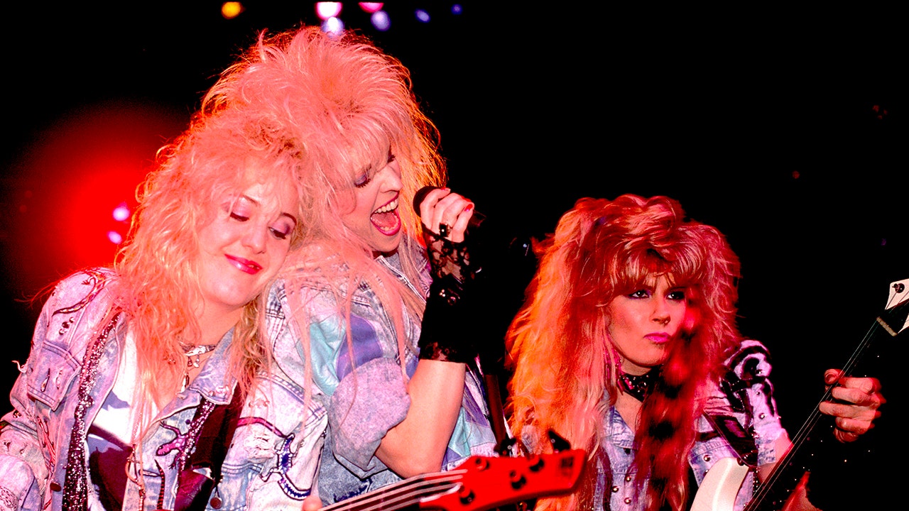 The band Vixen performing close to each other on stage wearing denim jackets