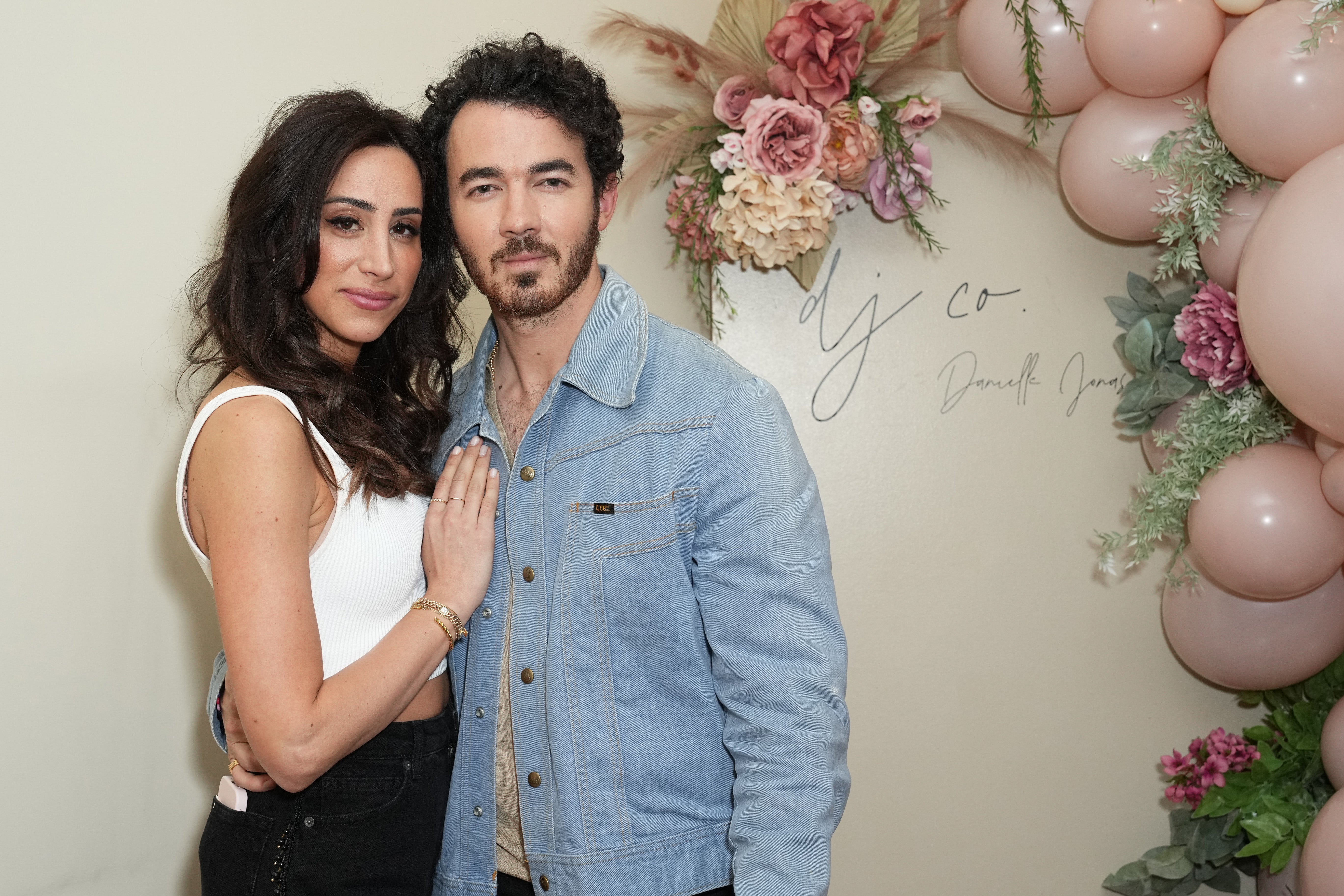 Kevin Jonas posing with wife Danielle Jonas in front of flower arch