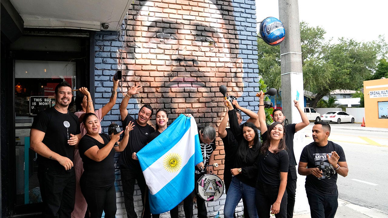 Staff pose in front of the Messi mural