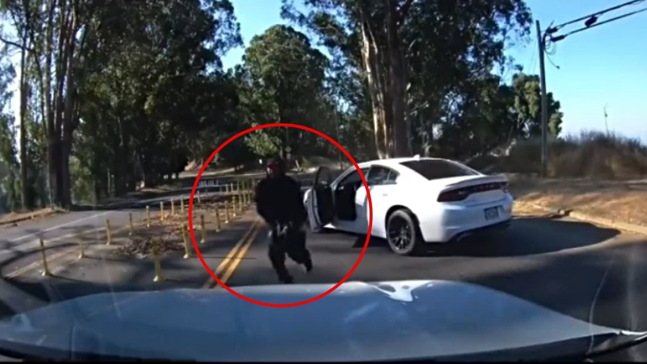 The driver suspect is seen exiting a Dodge Charger and pointing a gun toward the victim