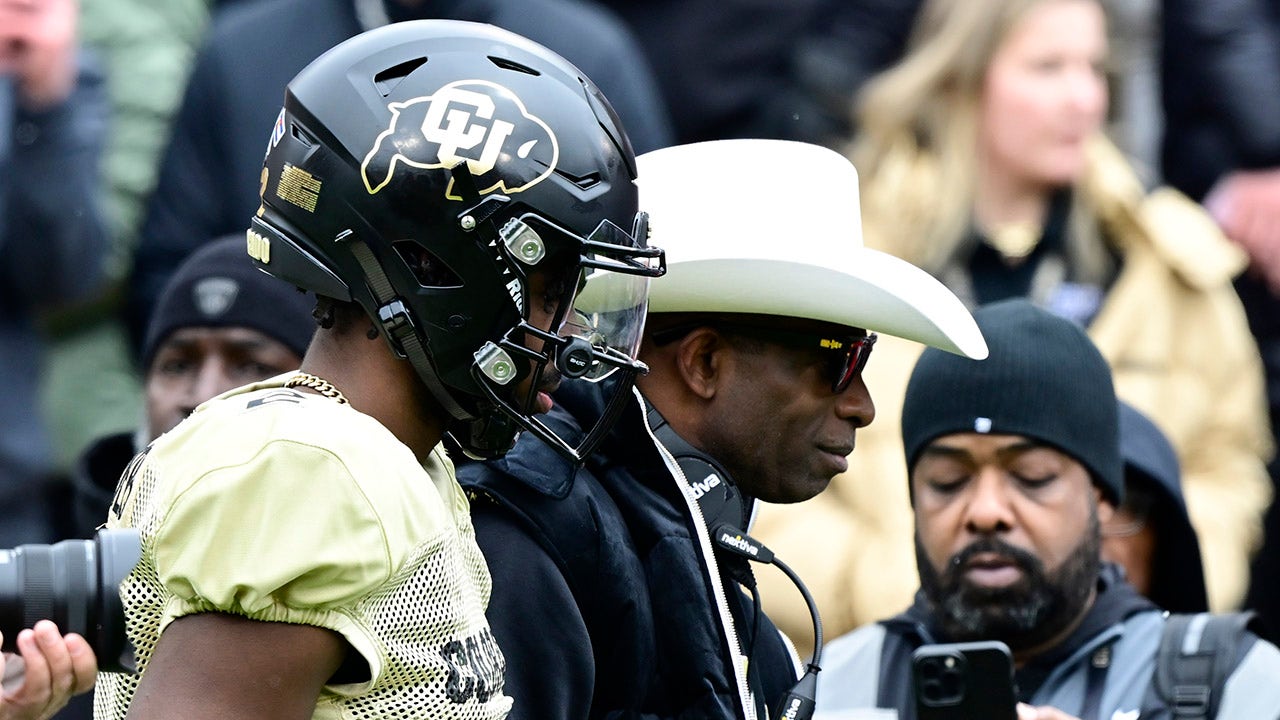 Colorado Buffaloes quarteback Shedeur Sanders walks with his father and coach Deion Sanders