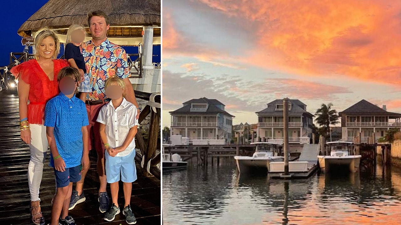 Shiver family poses with their children next to a photo of three homes in the Bahamas at sunset.