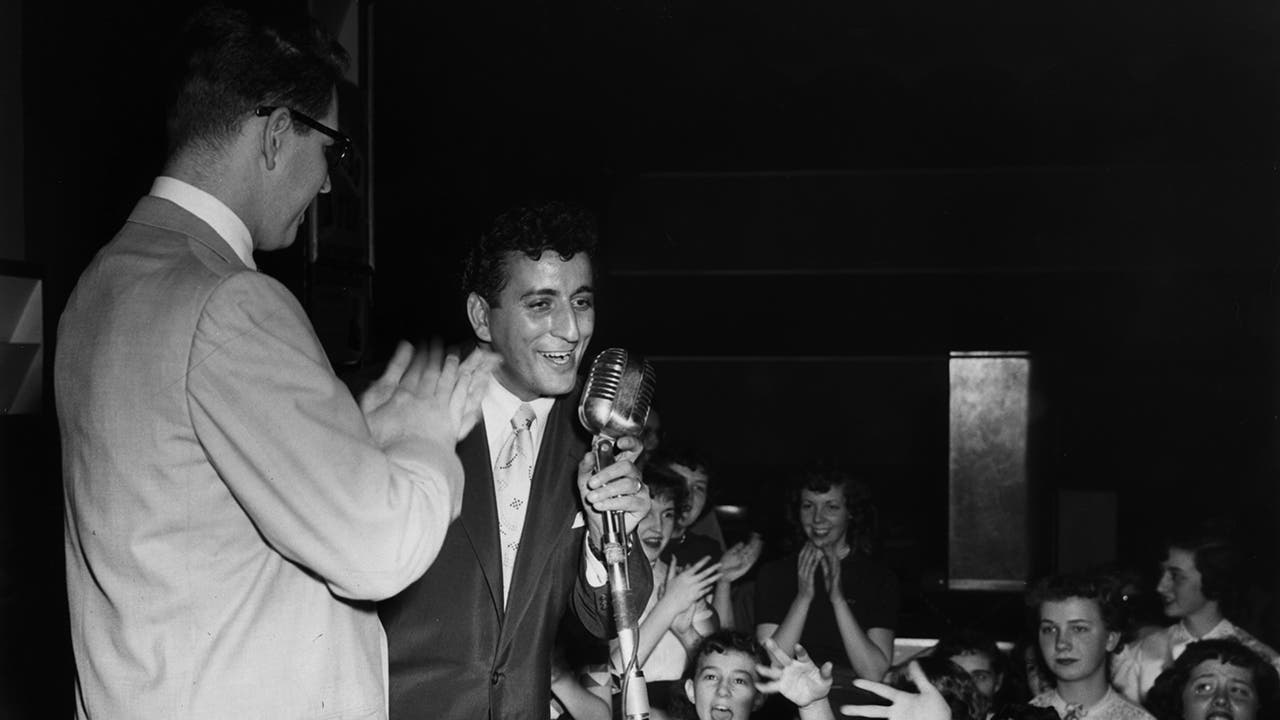 Young Tony Bennett performing on stage in front of a crowd.