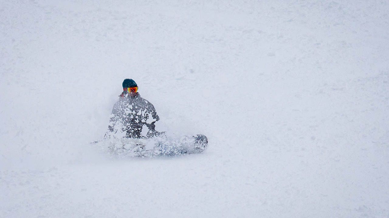 Un snowboarder desciende una colina