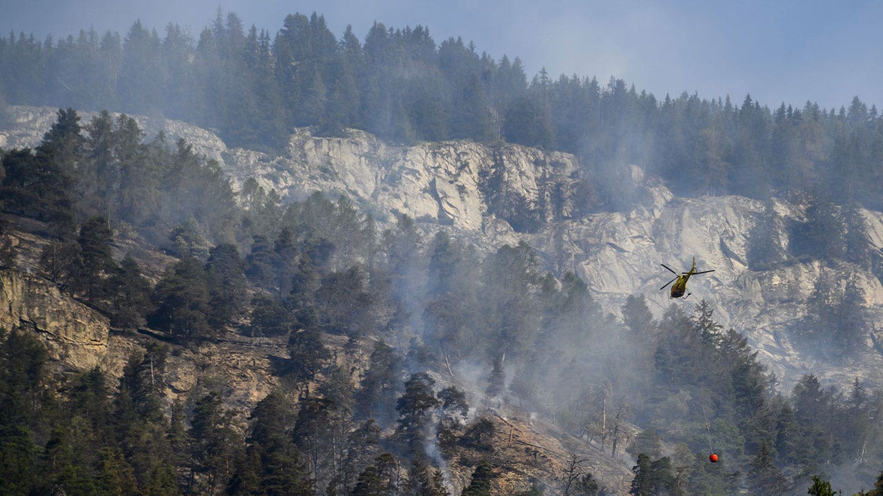 Hubschrauber schüttet Wasser auf Bergfeuer