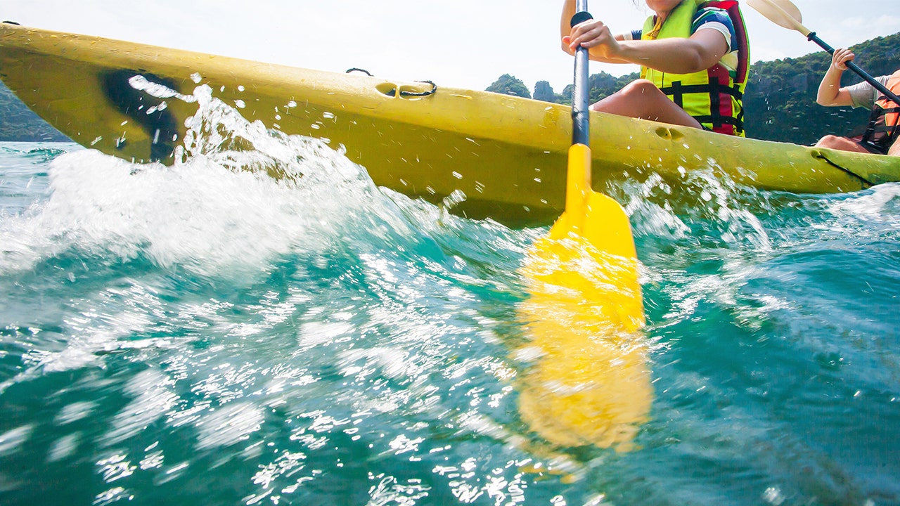 Person paddles oar while in kayak.