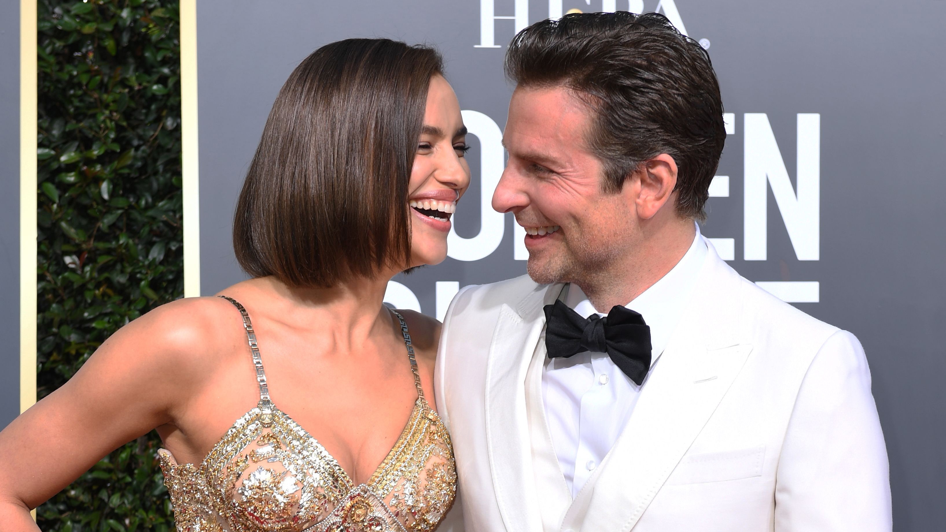 Irina Shayk and Bradley Cooper laugh at the Golden Globes award carpet