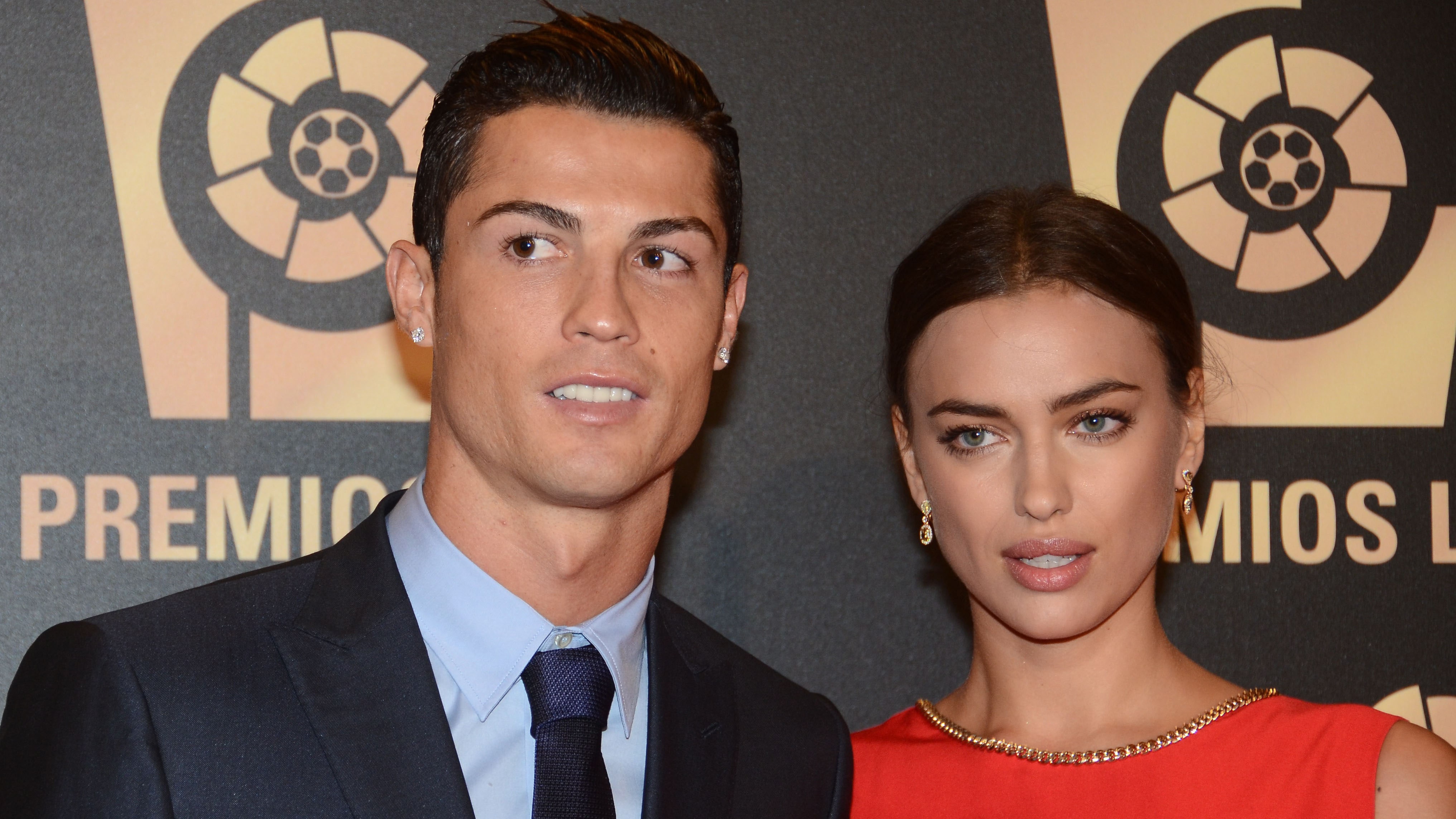 Cristiano Ronaldo looks to his right in a suit with Irina Shayk in red on the carpet