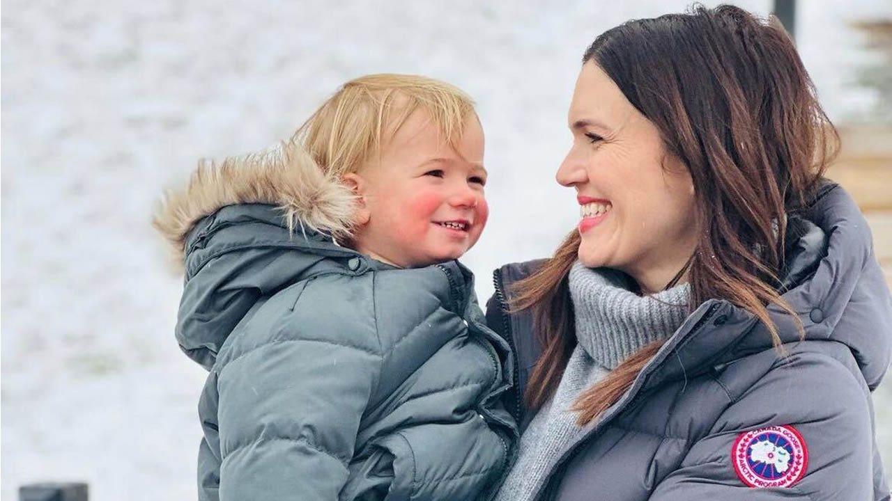 mandy moore holding son gus in the snow and smiling
