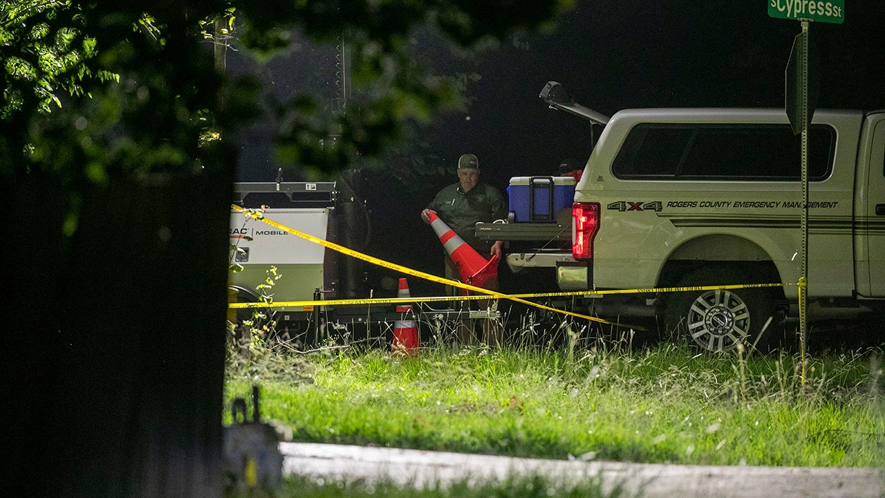 A police officer unloads orange cones from an SUV at the crime scene