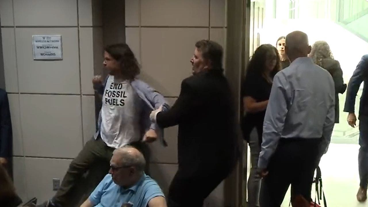 Protestor being yanked out of auditorium