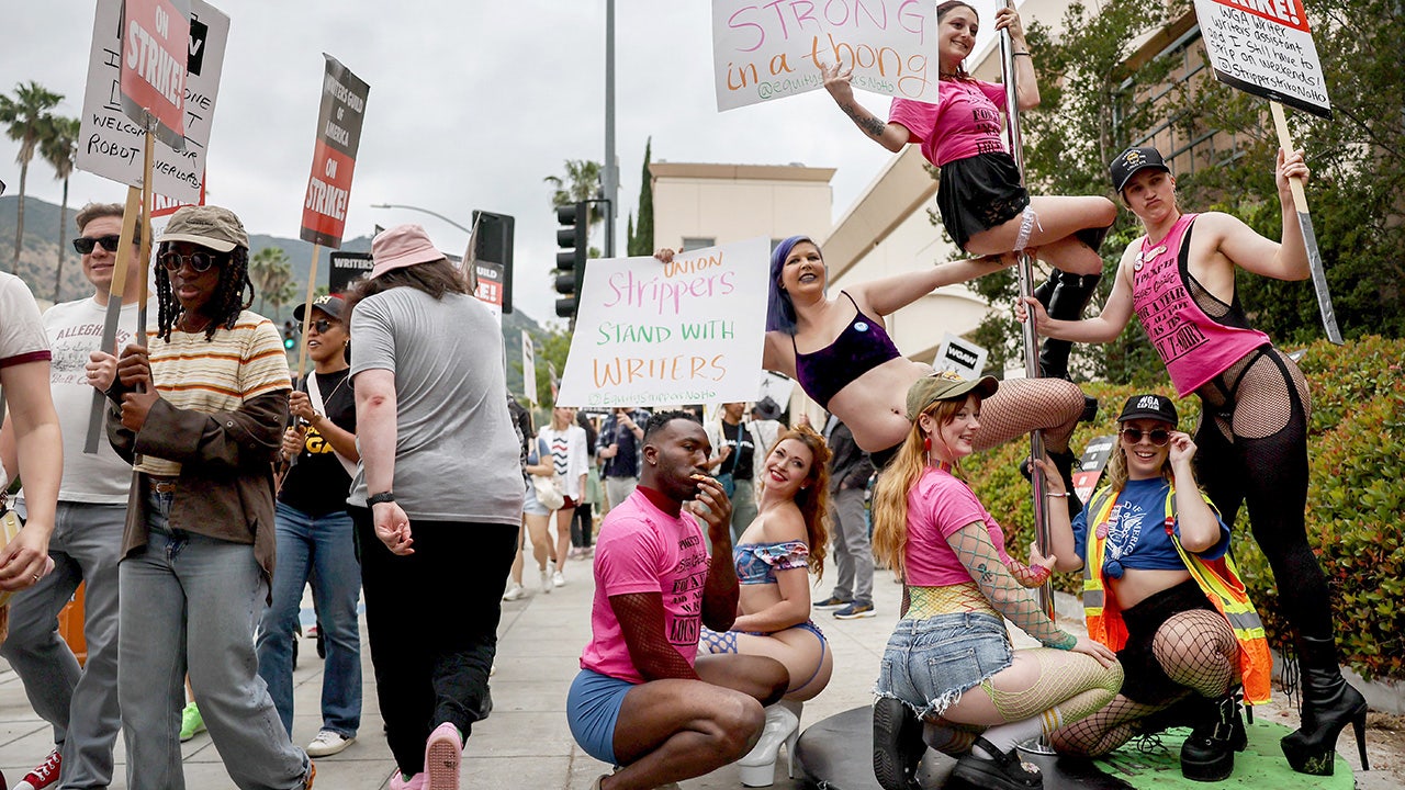 Strippers hold signs and pose on a pole in Burbank, California