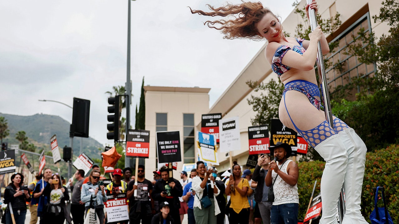 Stripper dances on a pole in Burbank, California while people hold signs in background