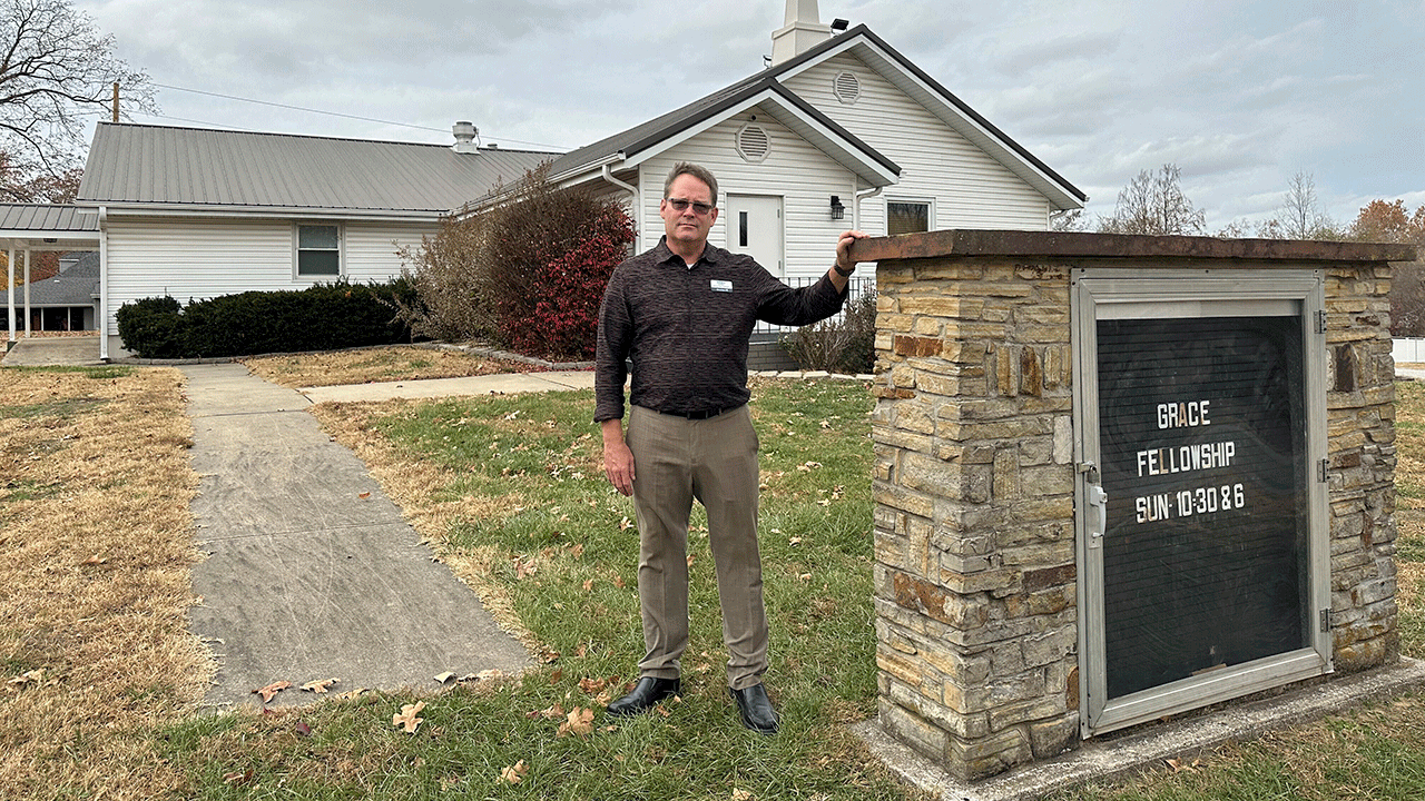 Pastor stands near sign