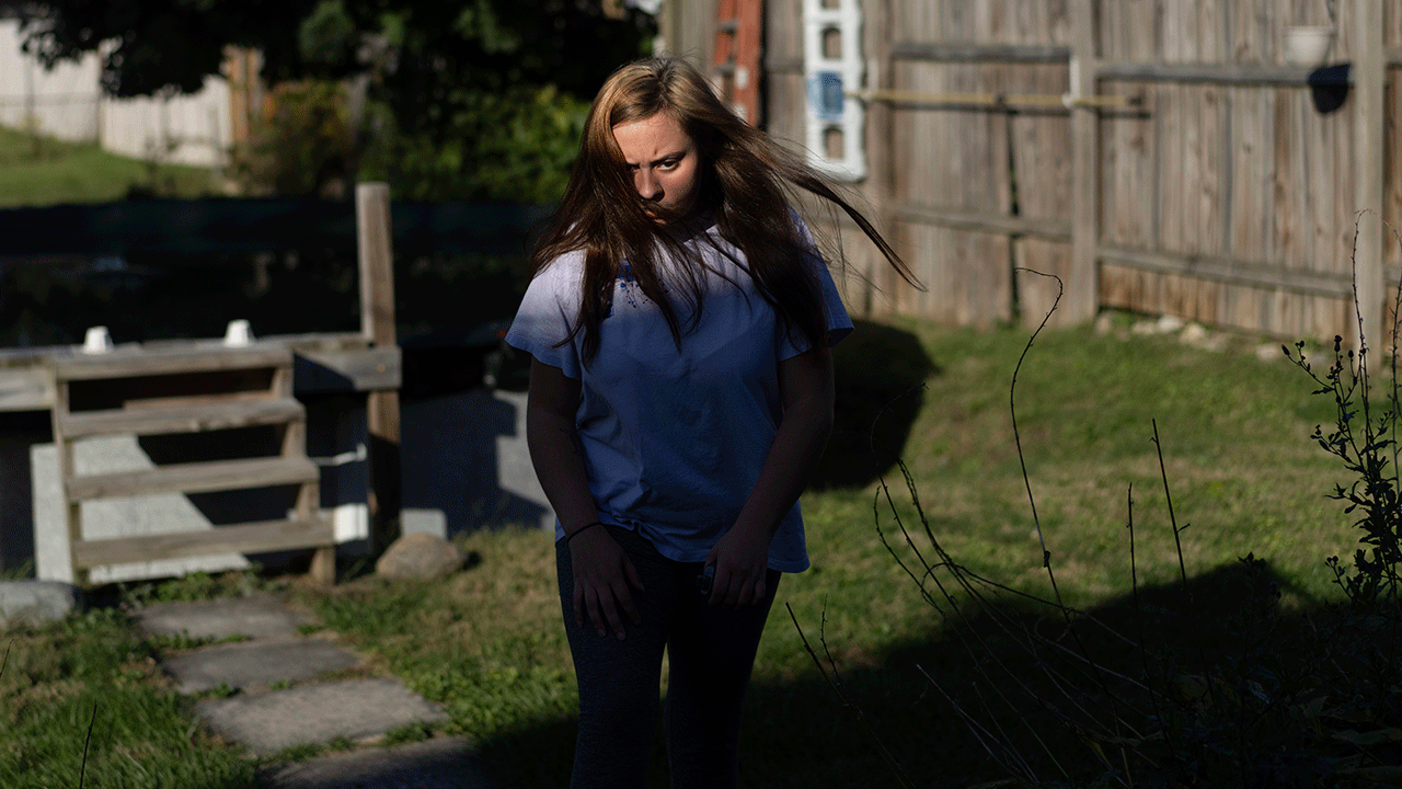 A teen girl walks through backyard