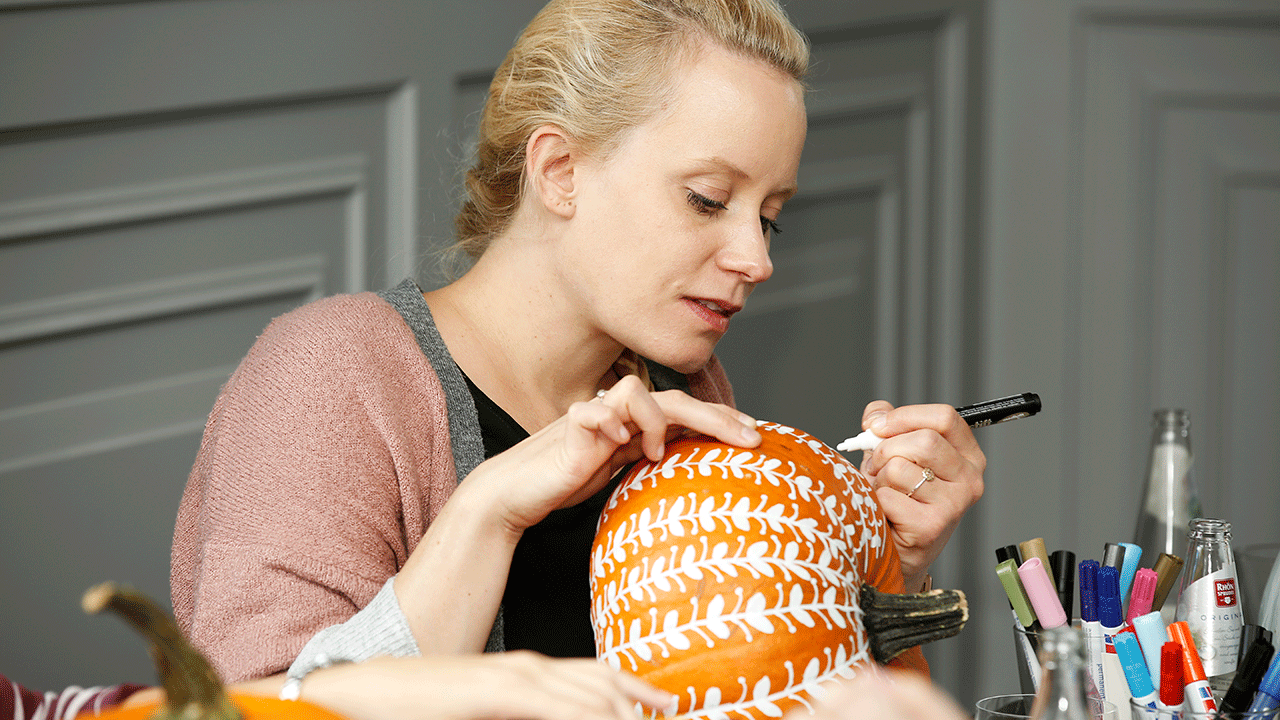 A woman painting pumpkins