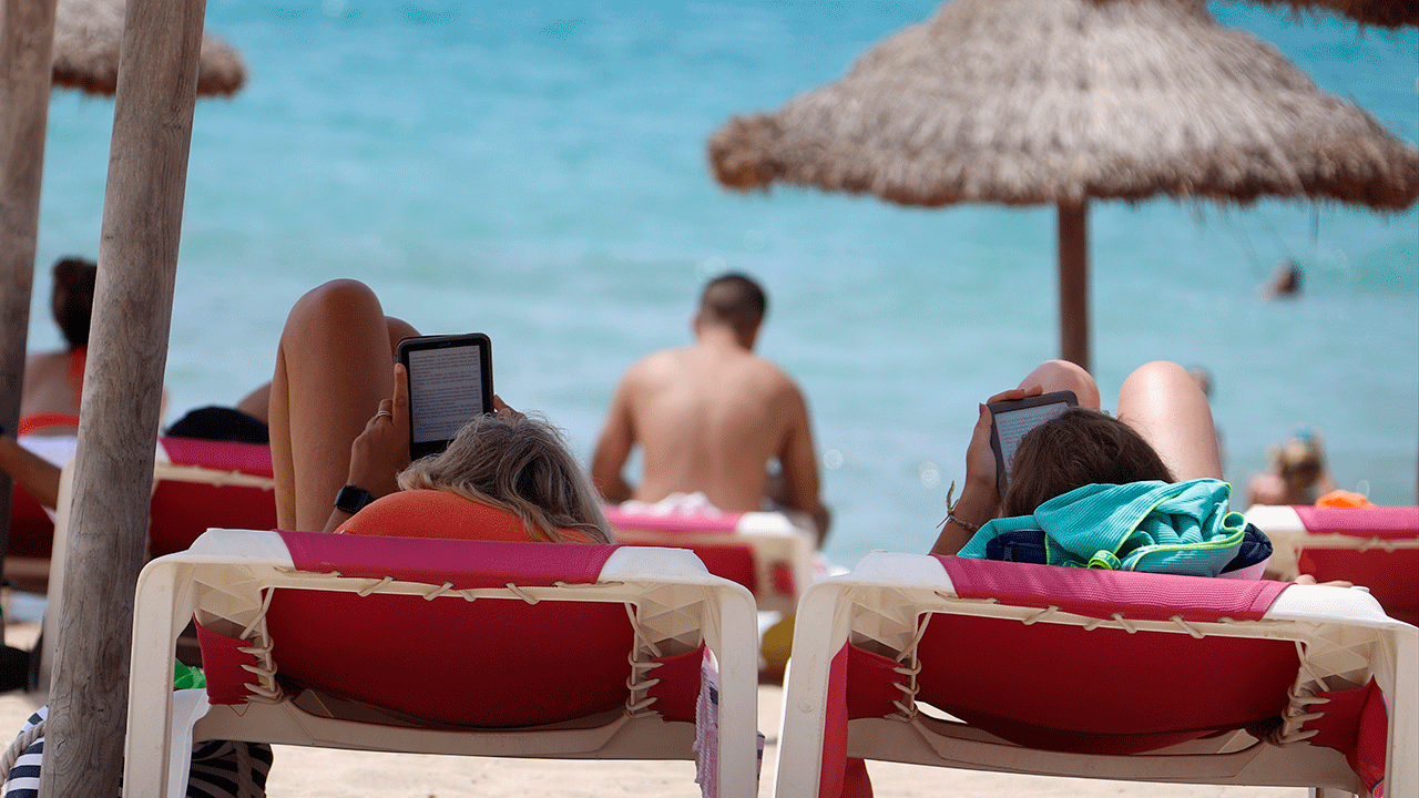 Two girls reading Kindles at the beach