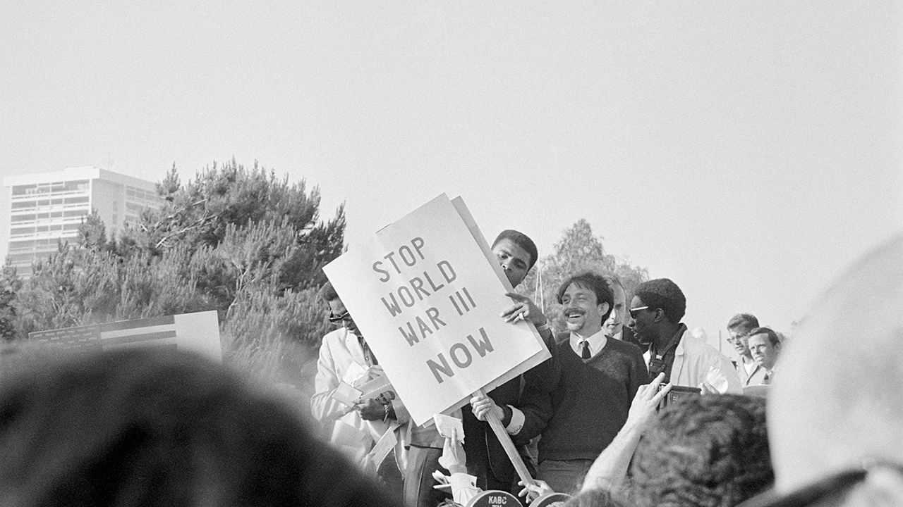 Muhammad Ali standing with picketers