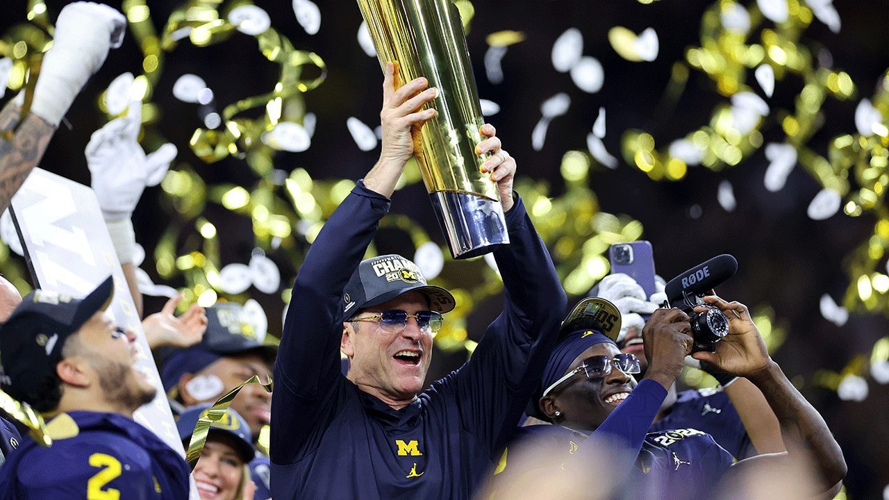 University of Michigan coach Jim Harbaugh holding up championship trophy