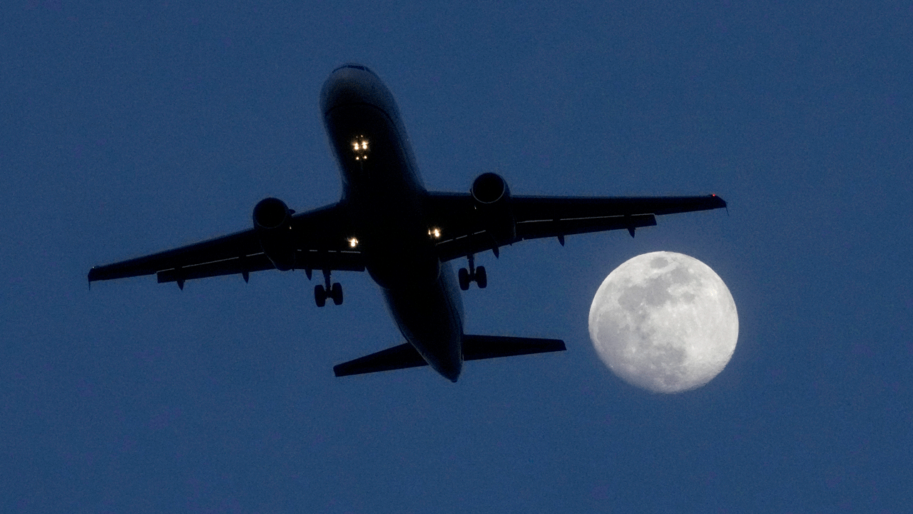 plane flying at night, the moon in the shot