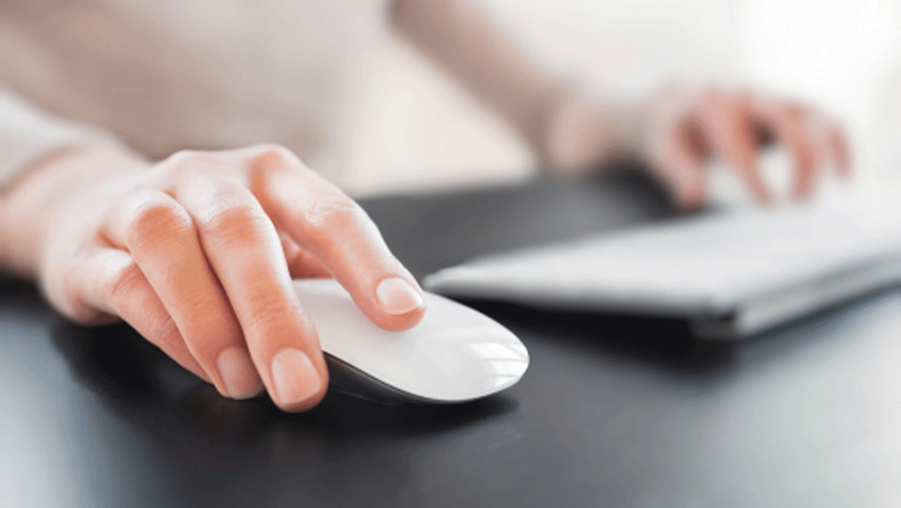 woman's hand on a computer mouse and keyboard