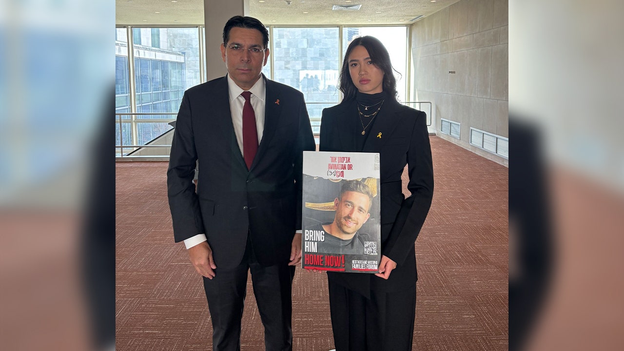 Israeli U.N. Ambassador Danny Danon stands beside freed Hamas hostage Noa Argamani as she holds a poster with her partner, Avinatan Or, who is still being held hostage in Gaza.