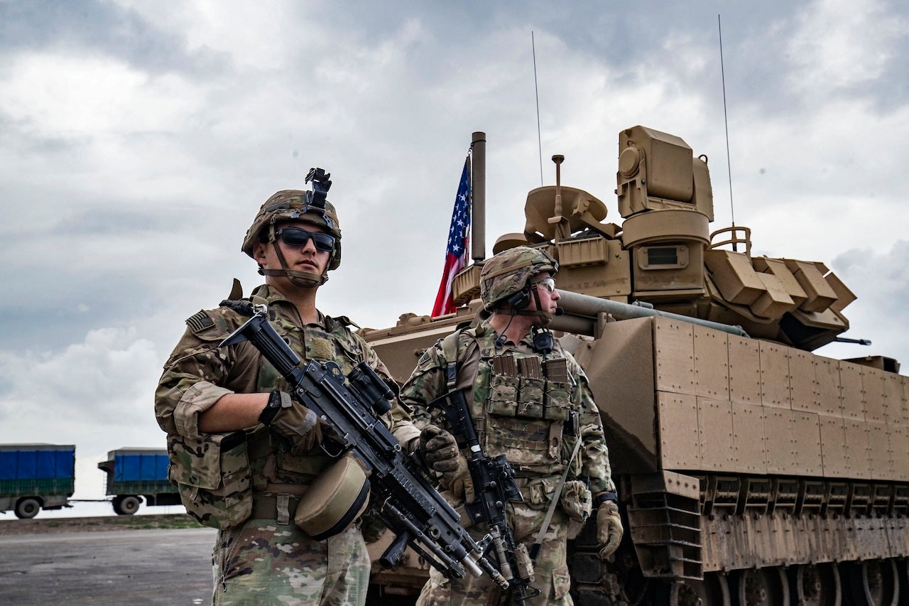 U.S. Army soldiers stand near an armored military vehicle on the outskirts of Rumaylan in Syria's northeastern Hasakeh province, bordering Turkey, on March 27, 2023. (Delil Souleiman/AFP via Getty Images)