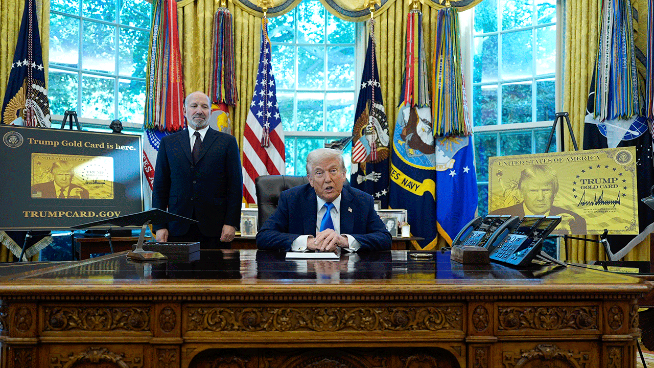 President Donald Trump speaks alongside Commerce Secretary Howard Lutnick, surrounded by posters showing the Trump Gold Card, in the Oval Office of the White House, Friday, Sept. 19, 2025, in Washington. ((AP Photo/Alex Brandon))