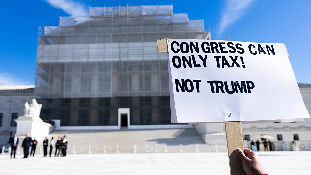 A protester holds a sign as the U.S. Supreme Court hears arguments on President Trump's tariffs on Wednesday, November 5, 2025. (Bill Clark/CQ-Roll Call, Inc via Getty Images) (Bill Clark/CQ-Roll Call, Inc via Getty Images)