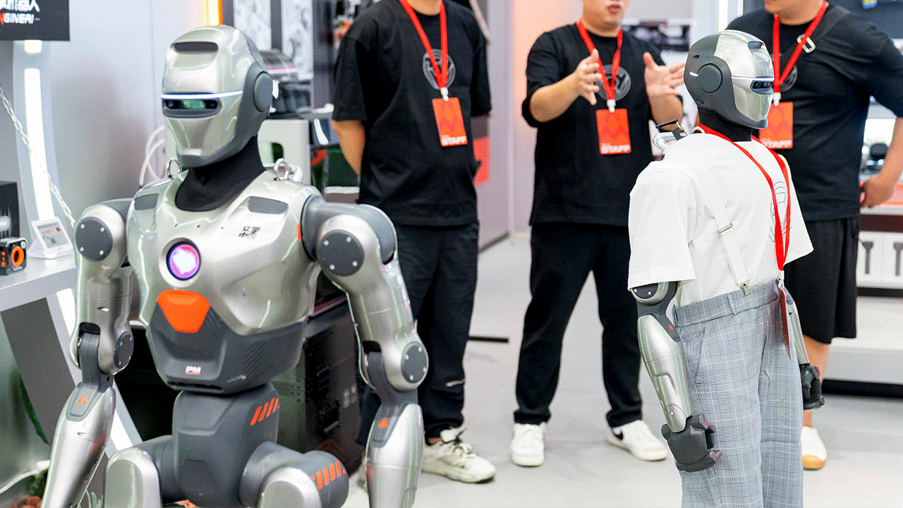 Two EngineAI PM01 robots stand like men holding red badges towards them.
