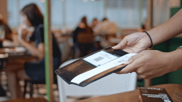 A woman's hand sets a credit card in the check holder to pay her bill at a restaurant.