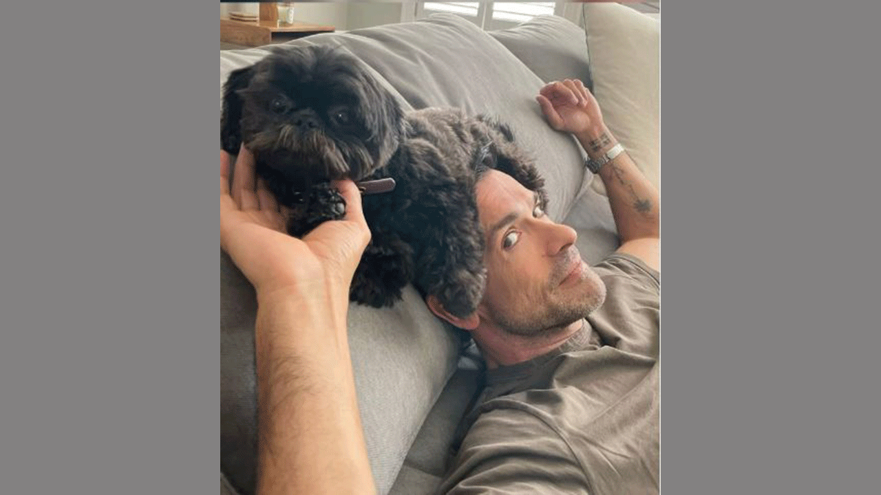 Mark Consuelos balancing his dog, Lena, on his head
